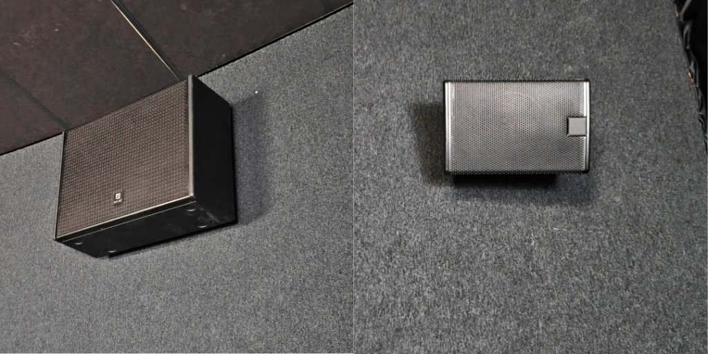 Two black wall-mounted speakers: a large left main cabinet and a smaller right satellite.